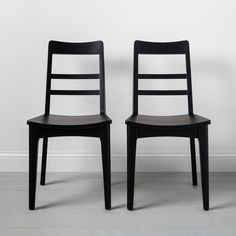 two black chairs sitting side by side against a white wall