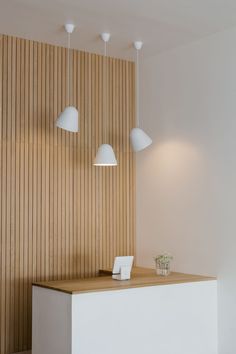 a white counter sitting in front of a wall with three lamps on top of it