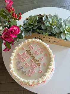 a birthday cake sitting on top of a table next to a vase with flowers and succulents