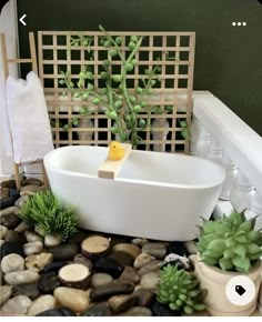 a white bath tub sitting on top of a pile of rocks next to a potted plant