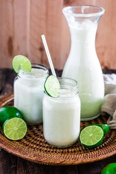 two mason jars filled with limeade sitting on top of a wooden table next to sliced limes