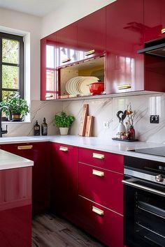 a kitchen with red cabinets and white counter tops is pictured in this image, there are plants on the window sill