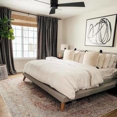 a large bed sitting in the middle of a bedroom next to a painting on the wall