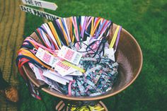 there is a basket full of different colored ribbons in the grass next to a sign