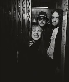 three people are posing for a black and white photo in an elevator with their arms around each other