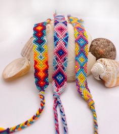 several bracelets and seashells on a white surface with one beaded in different colors