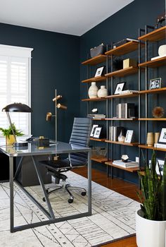 a home office with blue walls and wooden shelving, along with a black leather chair