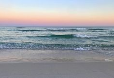 the ocean waves are rolling in and out on the beach at sunset or sunrise time