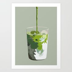 a glass filled with green liquid on top of a white table next to a wall