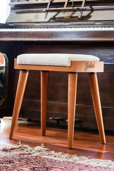 a piano sitting on top of a hard wood floor next to a chair and rug