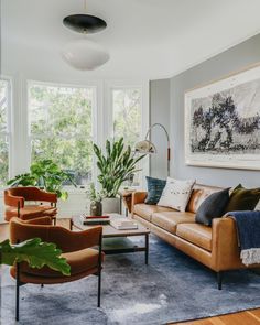 a living room with couches, chairs and a painting on the wall above them