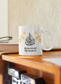 a white coffee mug with the words raman mubarak on it sitting on a table