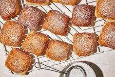 several square pastries on a cooling rack with powdered sugar