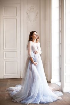 a pregnant woman in a white dress is posing for the camera with her hands on her belly