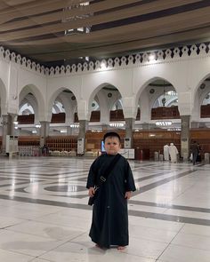 a little boy standing in the middle of a large building