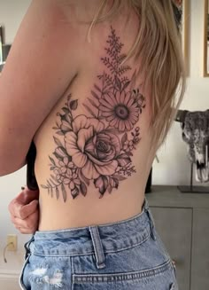 a woman's back with flowers and leaves tattooed on her upper half - body