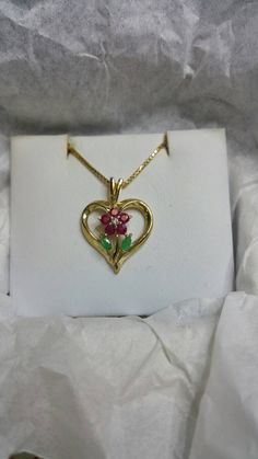 "This beautiful estate flower and heart necklace has rubies and emeralds with a small diamond making the design of a flower  all set in the center of a heart.  Perfect as a Mother's necklace. The chain is a box link 18 inches If you have questions regarding this piece send me a message. Don't forget to favorite our shop to be notified of new listings. Thank you for shopping with us. We are family owned. We hope as you purchase a beautiful piece of jewelry from us you get as much enjoyment from w Anniversary Necklace With Heart Pendant And Flower Charm, Heart-shaped Emerald Necklaces For Anniversary, Heart-shaped Emerald Gemstone Necklace, Heart-shaped Emerald Necklace For Anniversary, Emerald Heart Gemstone Necklace, Emerald Heart Shaped Gemstone Necklace, Heart Pendant Jewelry With Flower Charm For Anniversary, Anniversary Jewelry Heart Pendant With Flower Charm, Anniversary Heart Pendant Jewelry With Flower Charm