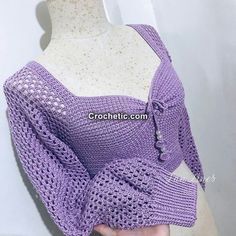 a close up of a person wearing a purple knitted top with an open shoulder