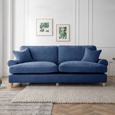 a blue couch sitting on top of a wooden floor next to a rug and wall