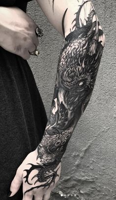 a man with a dragon tattoo on his arm and hand is holding something in his other hand