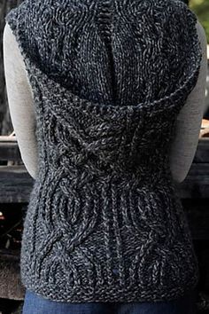 the back of a woman's sweater with an open knit pattern on it, in front of a wooden bench