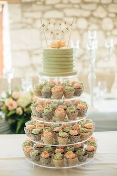 a tiered cake with cupcakes on it