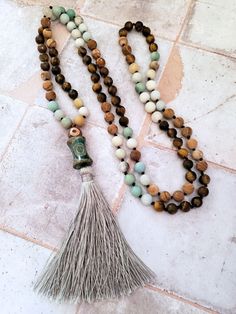 This beautiful Mala Necklace is made with 108 beads of Amazonite, Tiger's Eye, and Picture Jasper, each with its own unique healing properties. The Accent Dzi beads are believed to have protective and healing properties. This Mala necklace is not only a stunning accessory but also a tool for meditation and mindfulness. The necklace is hand-knotted between each bead and finished with a tassel under the Dzi beads.Materials & style:- 108 beads for traditional Mala use- Dzi beads for spiritual signi Multicolor Necklaces With 108 Beads For Meditation, Spiritual Beaded Mala For Healing, 8mm Holistic Healing Beads, Holistic 8mm Beads For Healing, Holistic 8mm Healing Beads, Holistic Beaded Mala For Meditation, Artisan 108 Beads For Meditation, Spiritual Gemstone Beaded Necklaces, Artisan Hand Knotted Necklace For Meditation