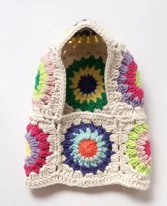 a crocheted purse with multicolored flowers on the front and bottom, sitting on a white surface