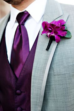 a man wearing a suit and tie with a purple flower on the lapel pin