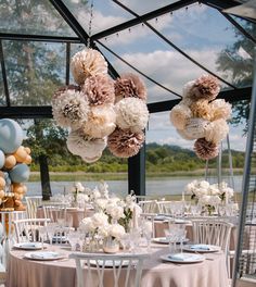 a table set up for a party with balloons and flowers hanging from it's ceiling