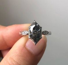 someone is holding an engagement ring with a diamond in the middle and two diamonds on each side