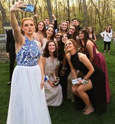 a group of people posing for a photo in front of some trees and one person taking a selfie