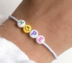 a person wearing a bracelet with smiley face beads on it's wrist and the word hope spelled in small letters