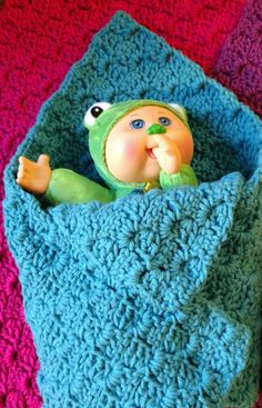 a crocheted blanket with a doll in it