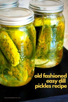 three jars filled with pickles sitting on top of a black table next to each other