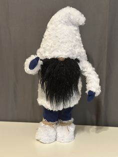 a white stuffed animal with black hair and beard