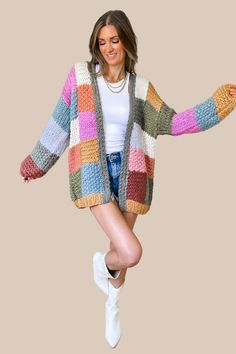 a woman is jumping in the air wearing a multicolored knitted cardigan