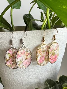 three pink and white flowers are hanging from earrings