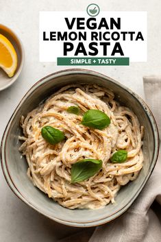 vegan lemon ricotta pasta in a bowl with basil leaves on top and an orange slice next to it