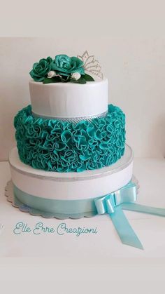 a three tiered cake decorated with blue flowers and ribbons on top of a white table