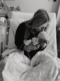 a woman in a hospital bed holding a baby and listening to headphones on her ear