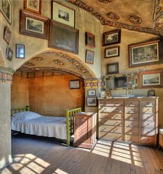 an old fashioned bedroom with many pictures on the wall and dresser in front of it