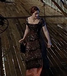 a woman walking down a wooden floor in a black and red dress with sequins on it