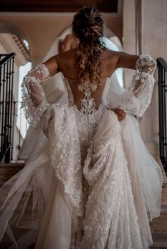 a woman in a wedding dress walking down stairs