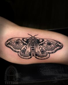 a black and white moth tattoo on the arm