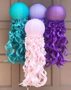 three paper lanterns hanging from the side of a door with purple, blue and green ribbons