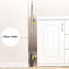 an image of the height of a broom in front of a white cabinet and door