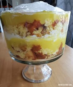 a cake sitting on top of a wooden table covered in frosting and toppings