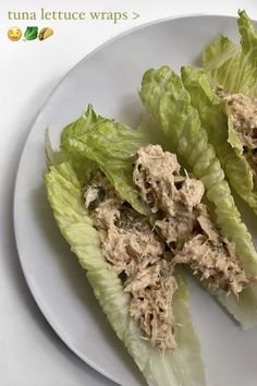 two lettuce wraps on a plate with tuna in the middle and green leaves