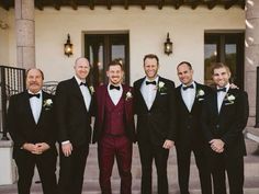 a group of men standing next to each other wearing suits and bow ties in front of a building